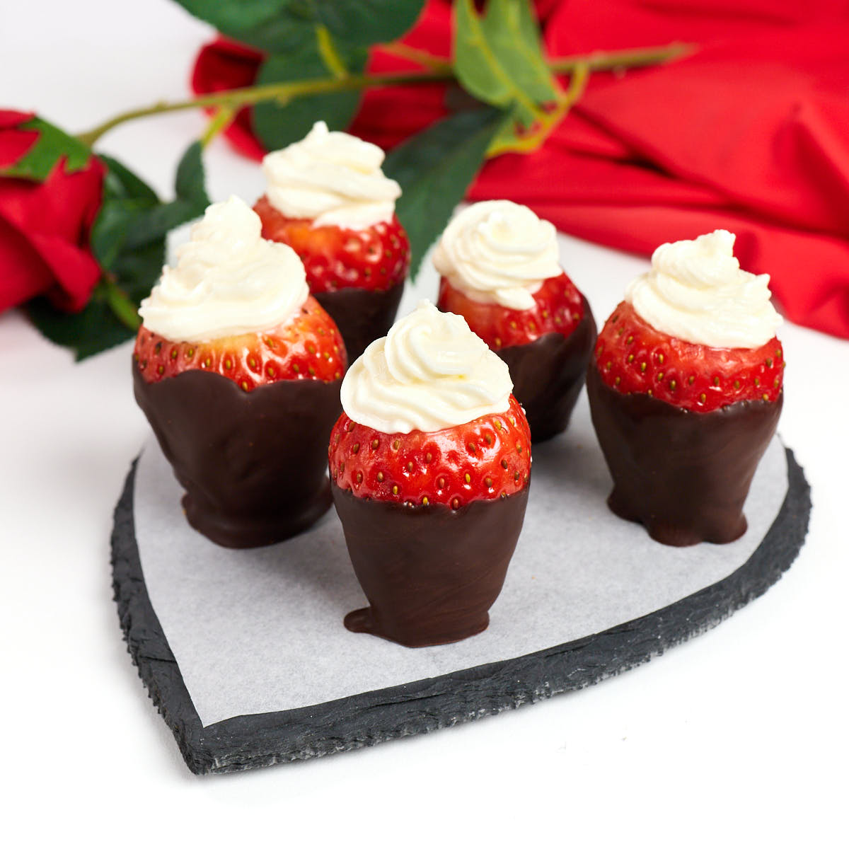 Chocolate covered cheesecake stuffed strawberries on a heart tray.
