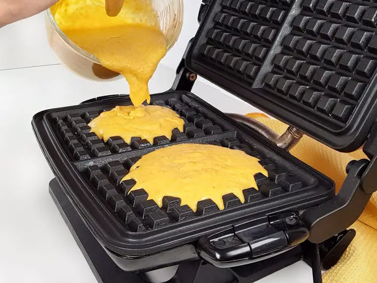 Pouring keto waffle batter in waffle iron.
