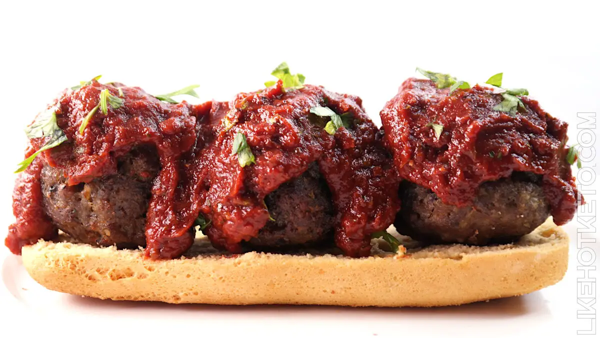 Almond flour meatballs on a slice of keto bread, topped with marinara sauce and chopped parley.