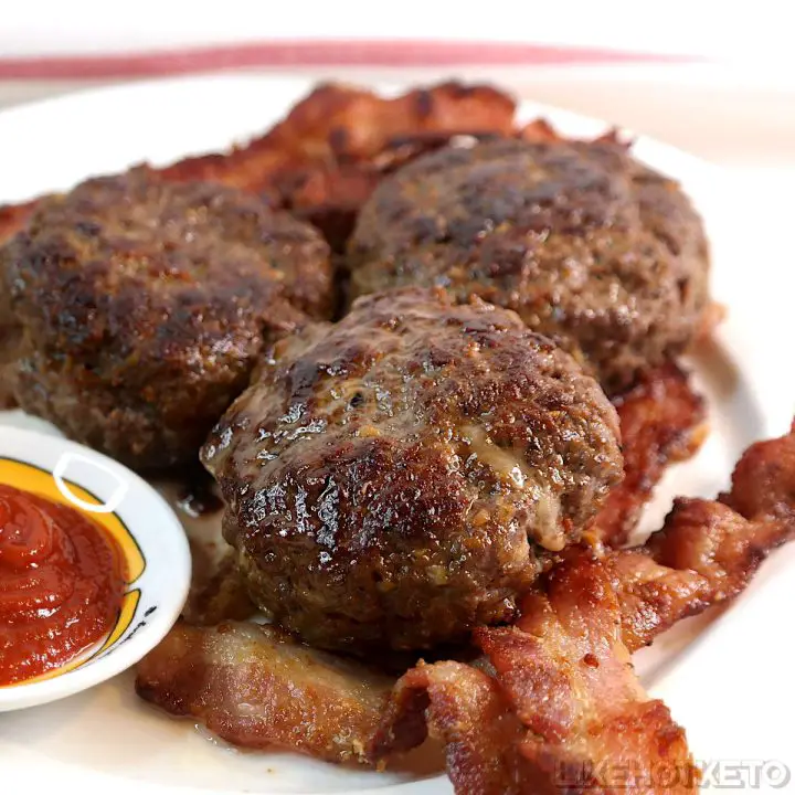 Keto air fried burgers stuffed with cheese over fried bacon.