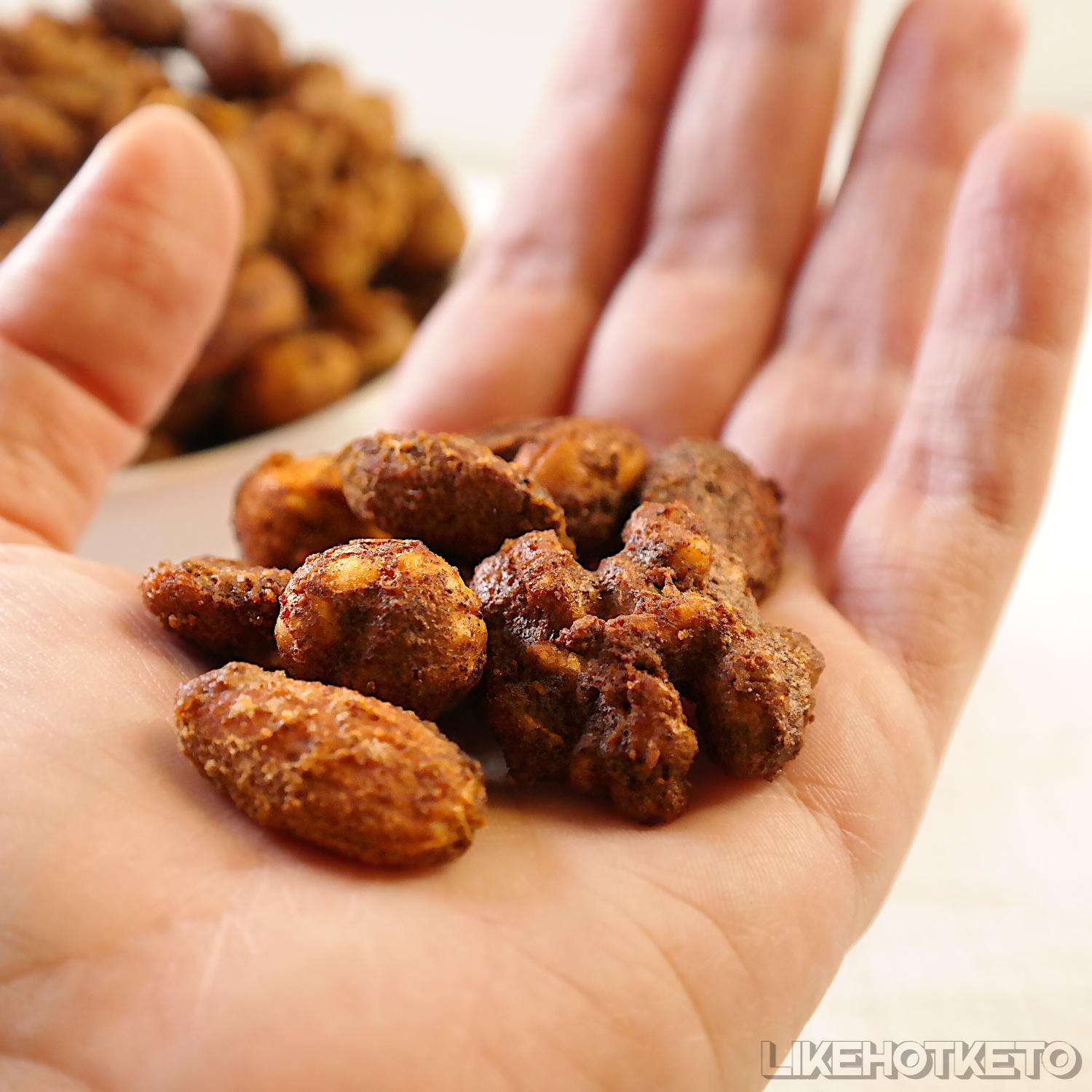 A hand full of keto cinnamon sugar-free candied nut mix.