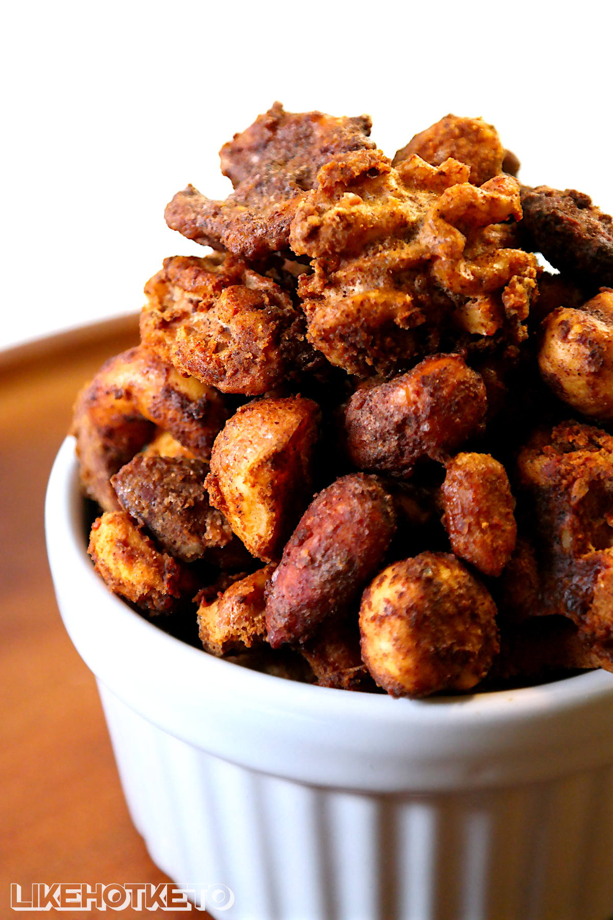 Keto cinnamon no-sugar candied nuts piled high in a white ramekin.