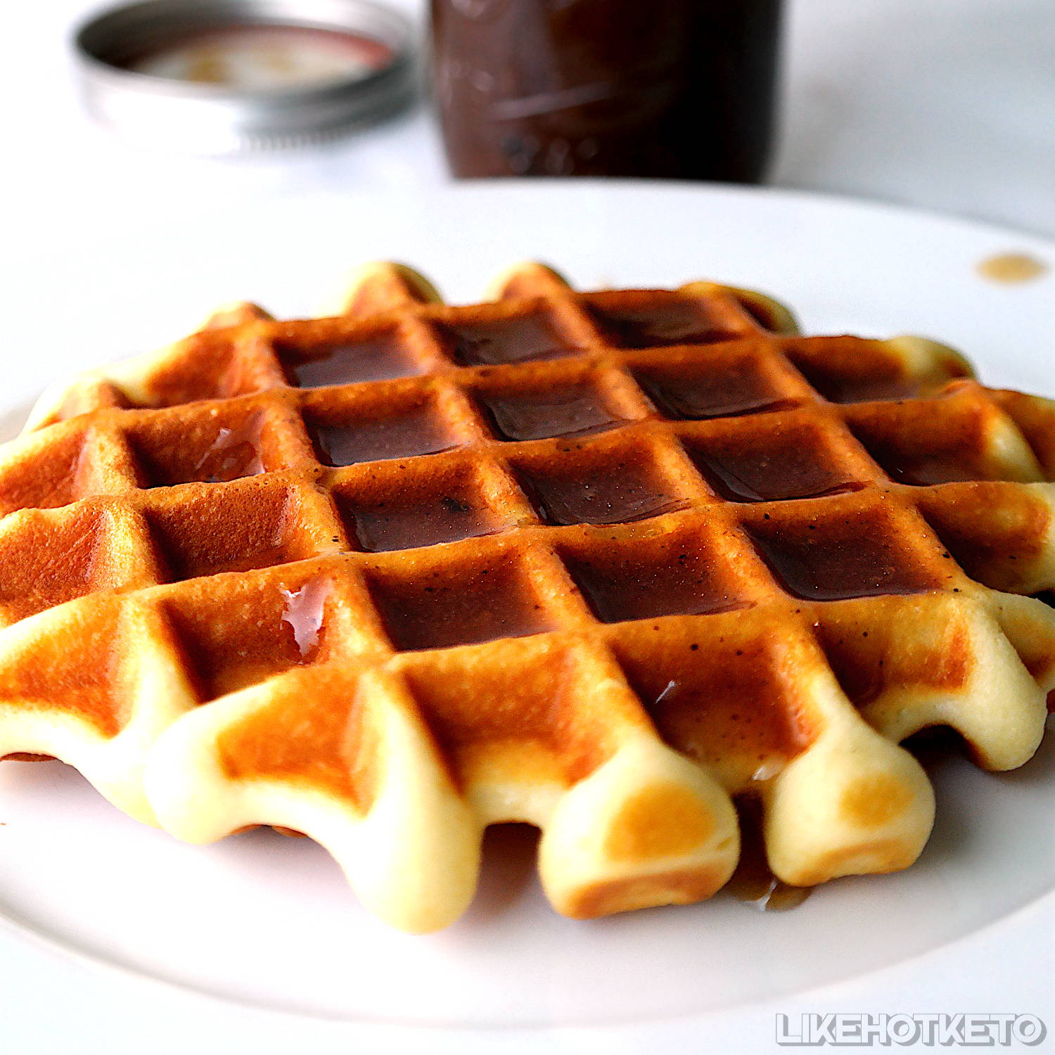 A huge, golden keto waffle covered in sugar-free maple syrup.