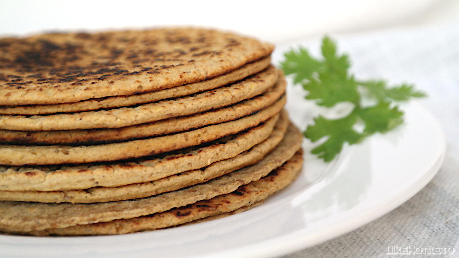 Flax meal tortillas piled up on a plate.