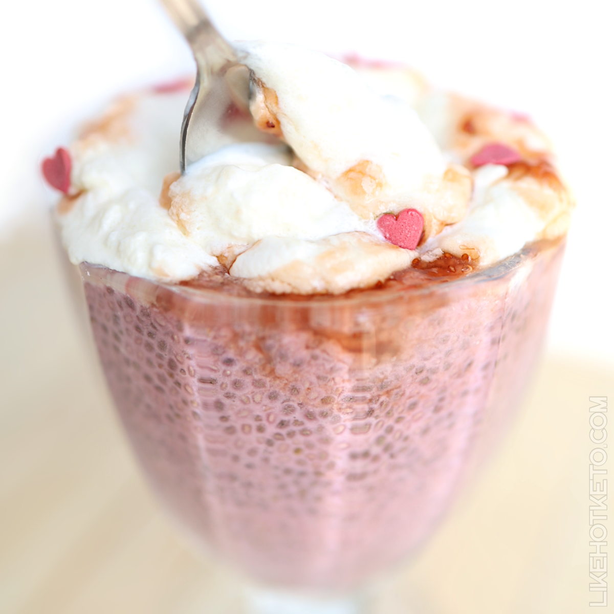 Bowl of strawberry protein chia pudding, topped with whipped cream.