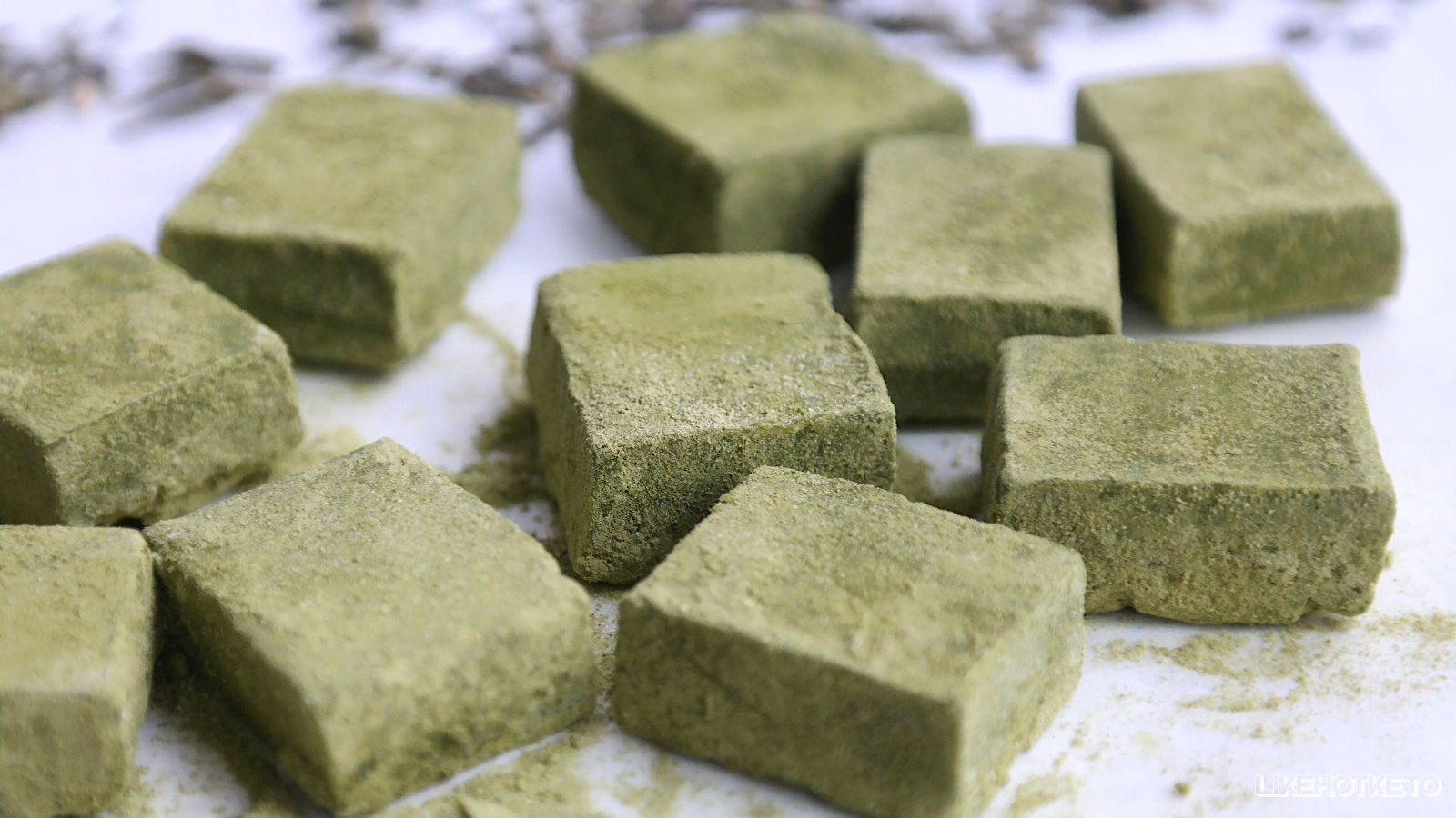 Squares of matcha sugar-free chocolate and a few green tea leaves.