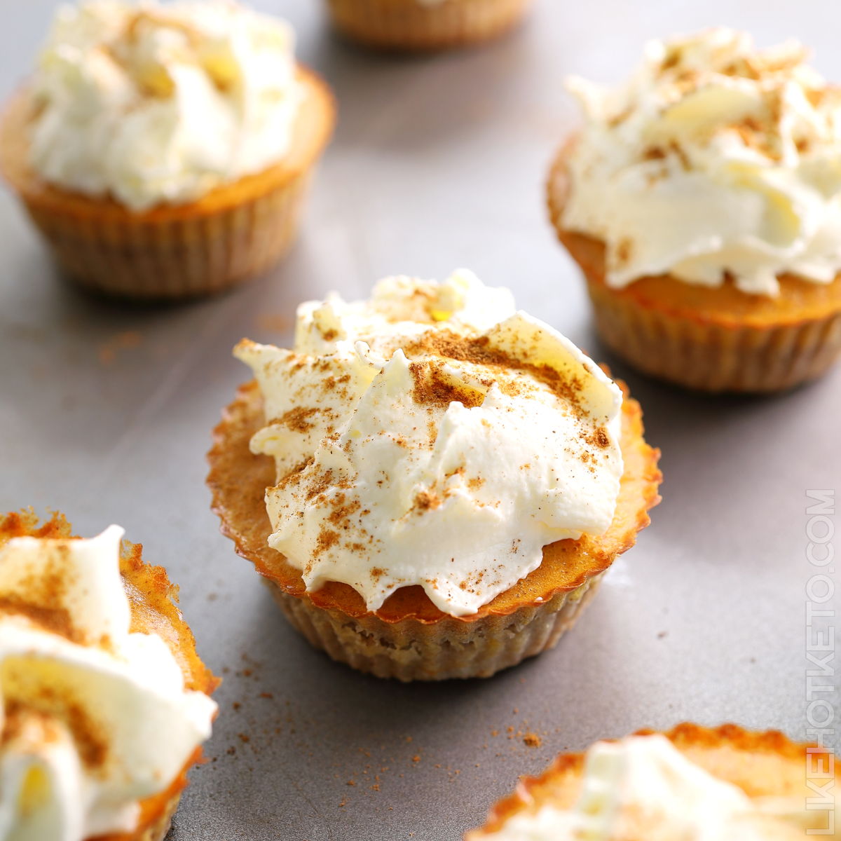 Mini keto pumpkin protein pies topped with whipped cream and cinnamon powder.