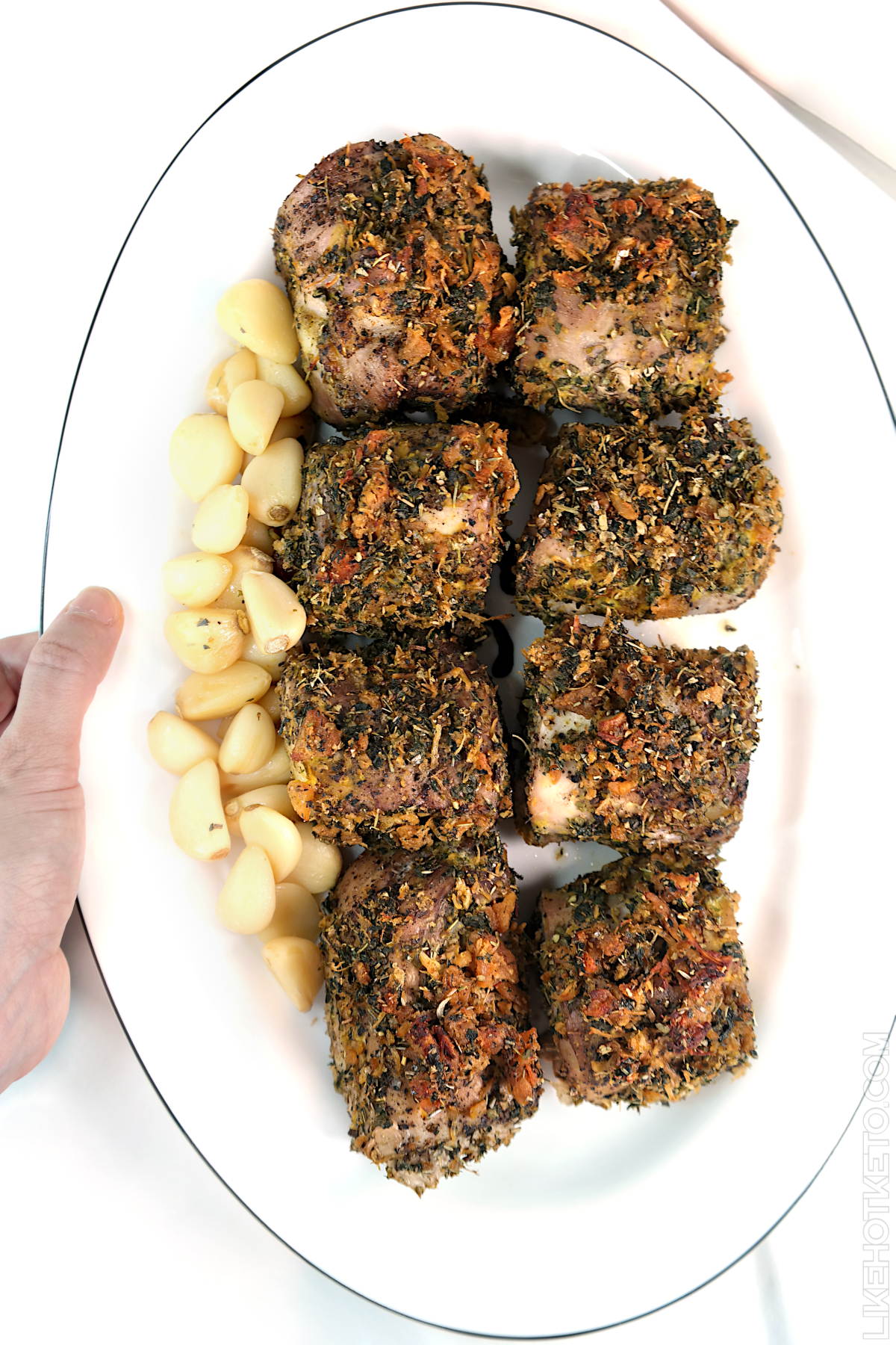 Seasoned roasted pork pieces on a serving plate with thyme, mint and oregano herb crust.