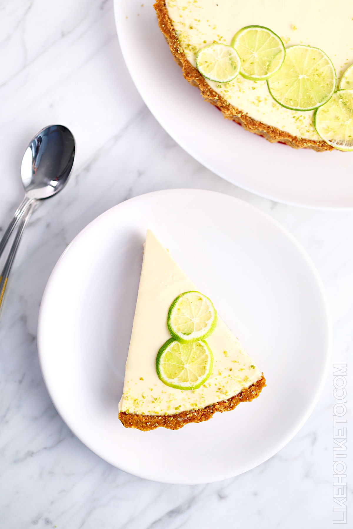 Sugar-free lime cheesecake pie served on a plate with a couple of spoons.