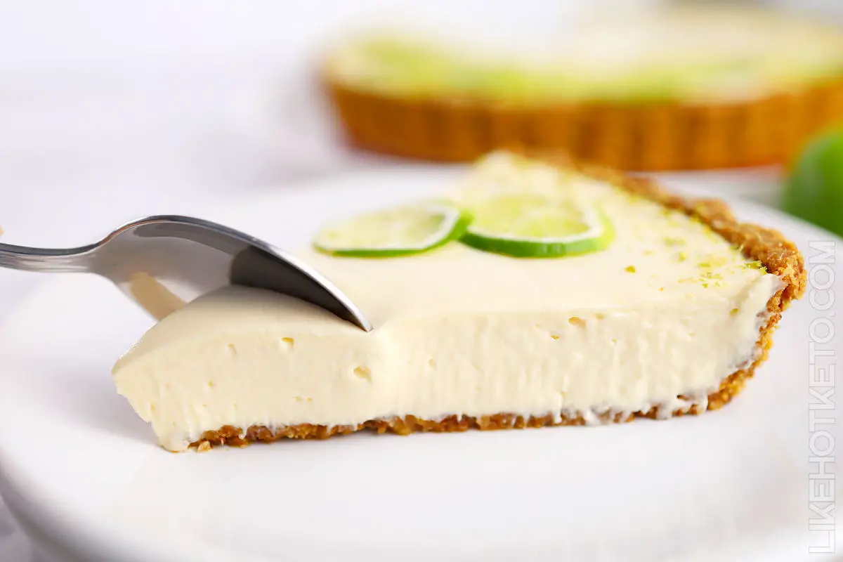Slice of Key lime pie cheesecake on a white plate.