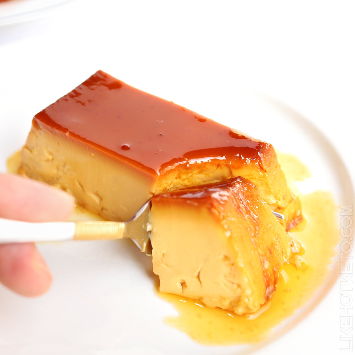 A slice of Portuguese pudding Abade de Priscos, topped with caramel, being sliced by a fork.