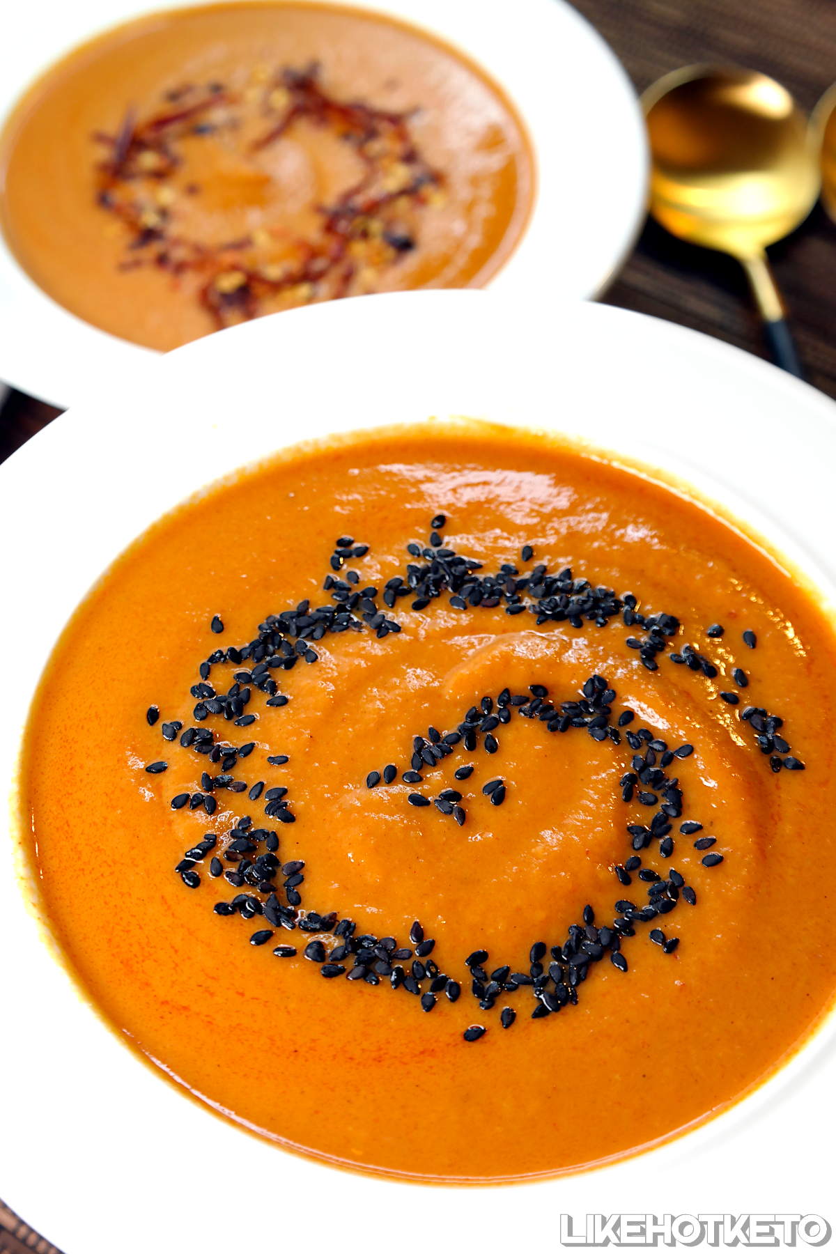 Keto pumpkin, coconut cream and ginger soup in a white bowl, garnished with sesame seeds.
