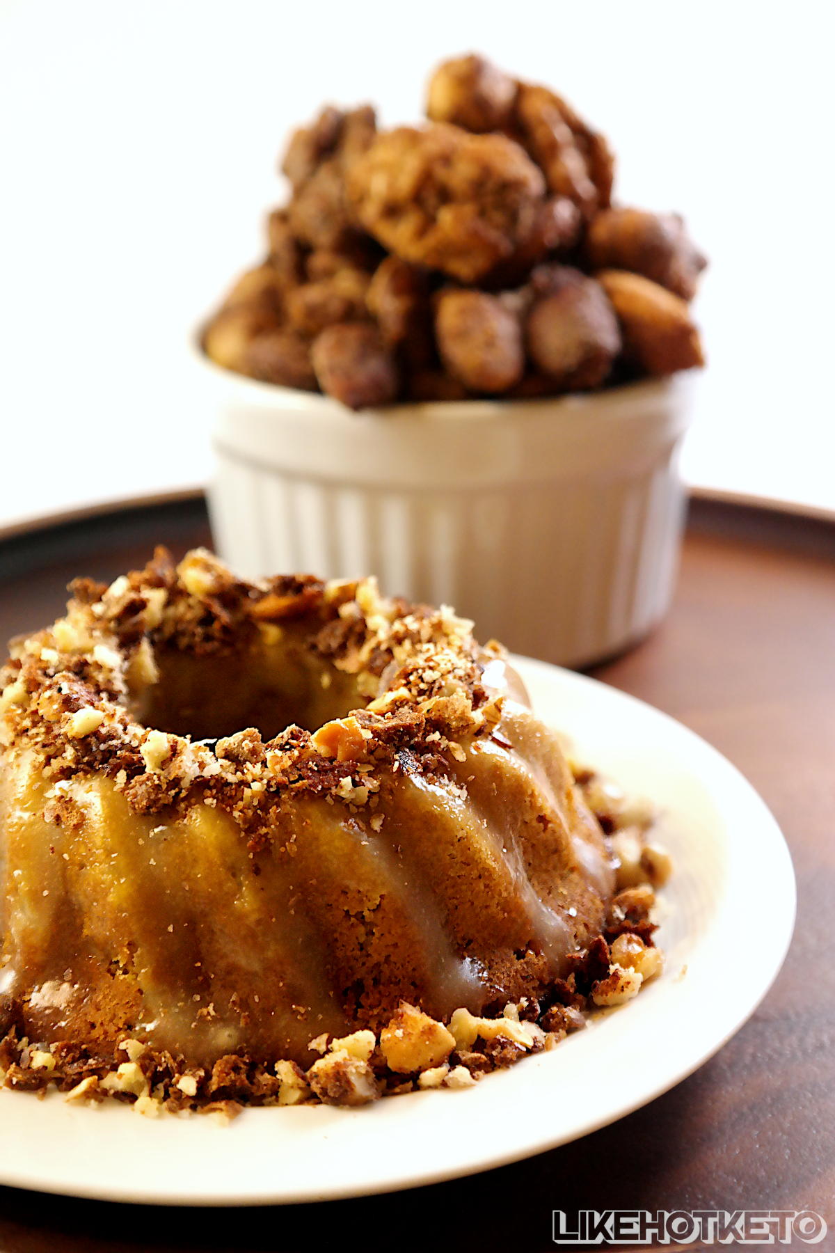 Gluten-free pumpkin pie spice mini bundt cake frosted with cream cheese and topped with cinnamon candied sugar-free crushed nuts.