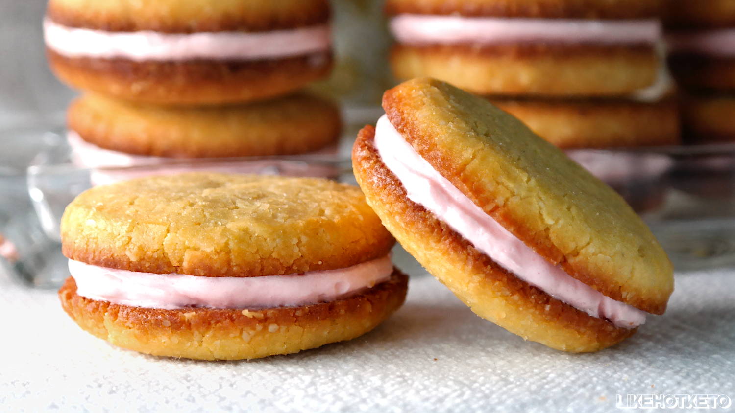 Keto strawberry cream sandwich cookies displayed atop a white cloth.