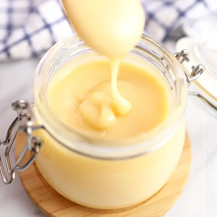Sugar-free sweetened condensed milk drizzling from a spoon into a mason jar.