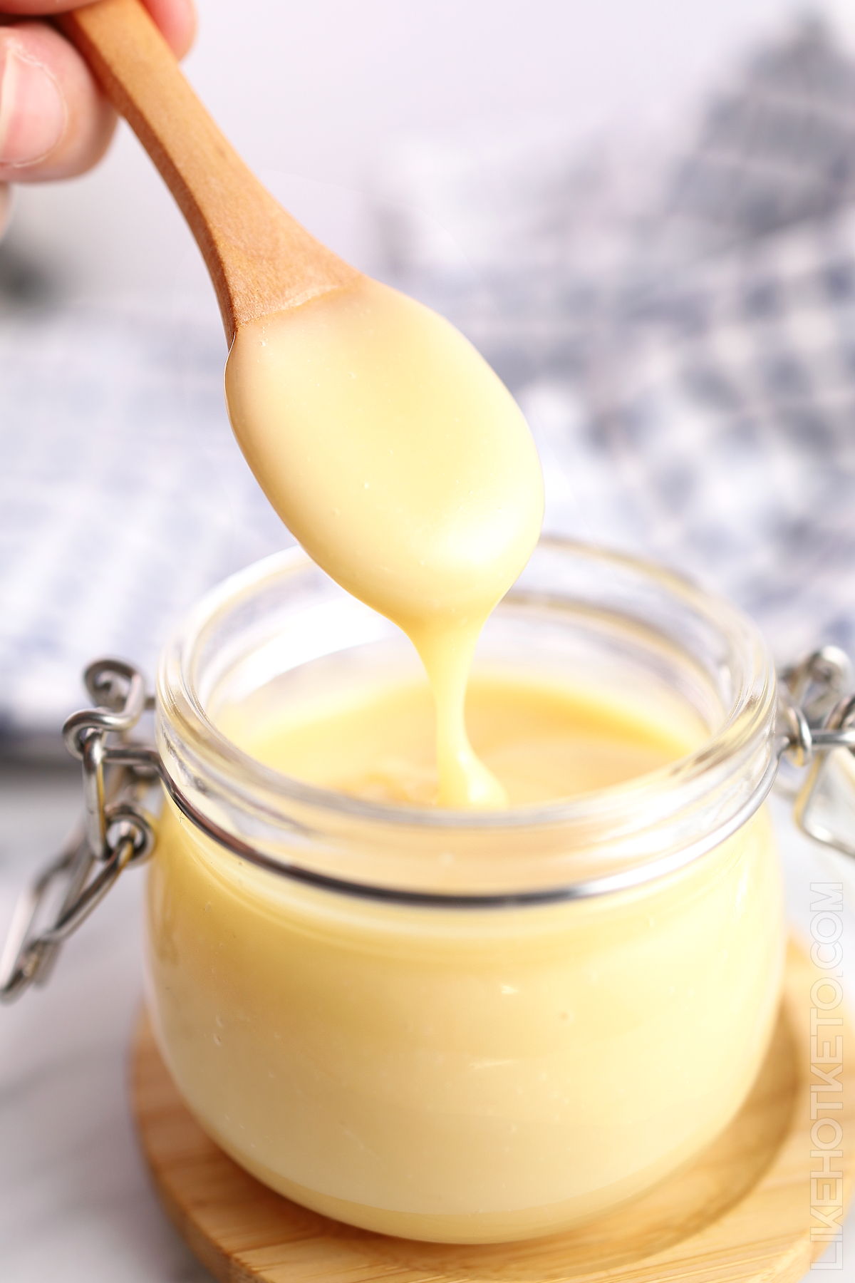 Homemade keto condensed milk getting spooned out of a mason jar.