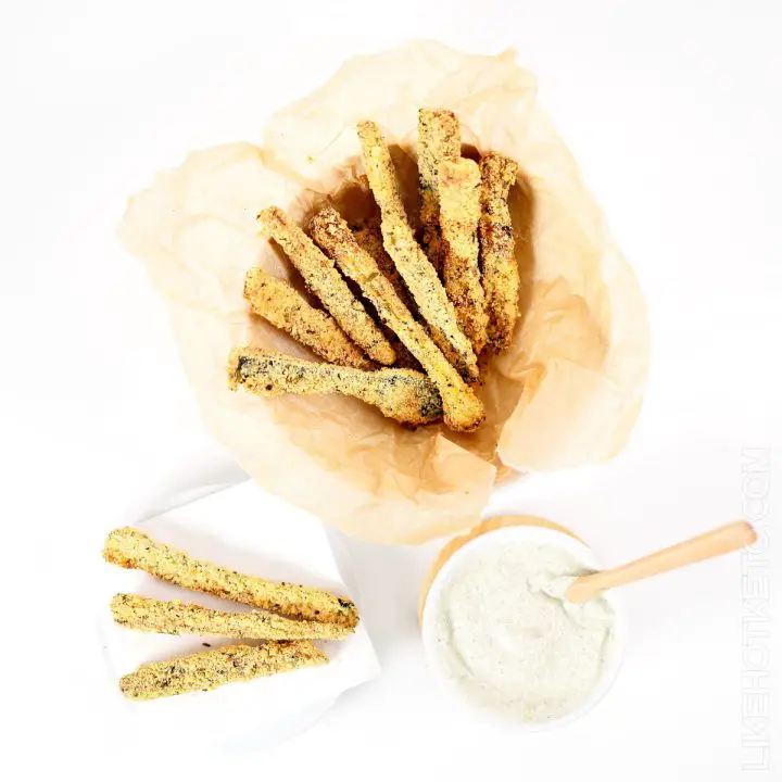 Basket full of zucchini fries, and zucchini fries served on a small plate with a side of ranch dipping sauce.