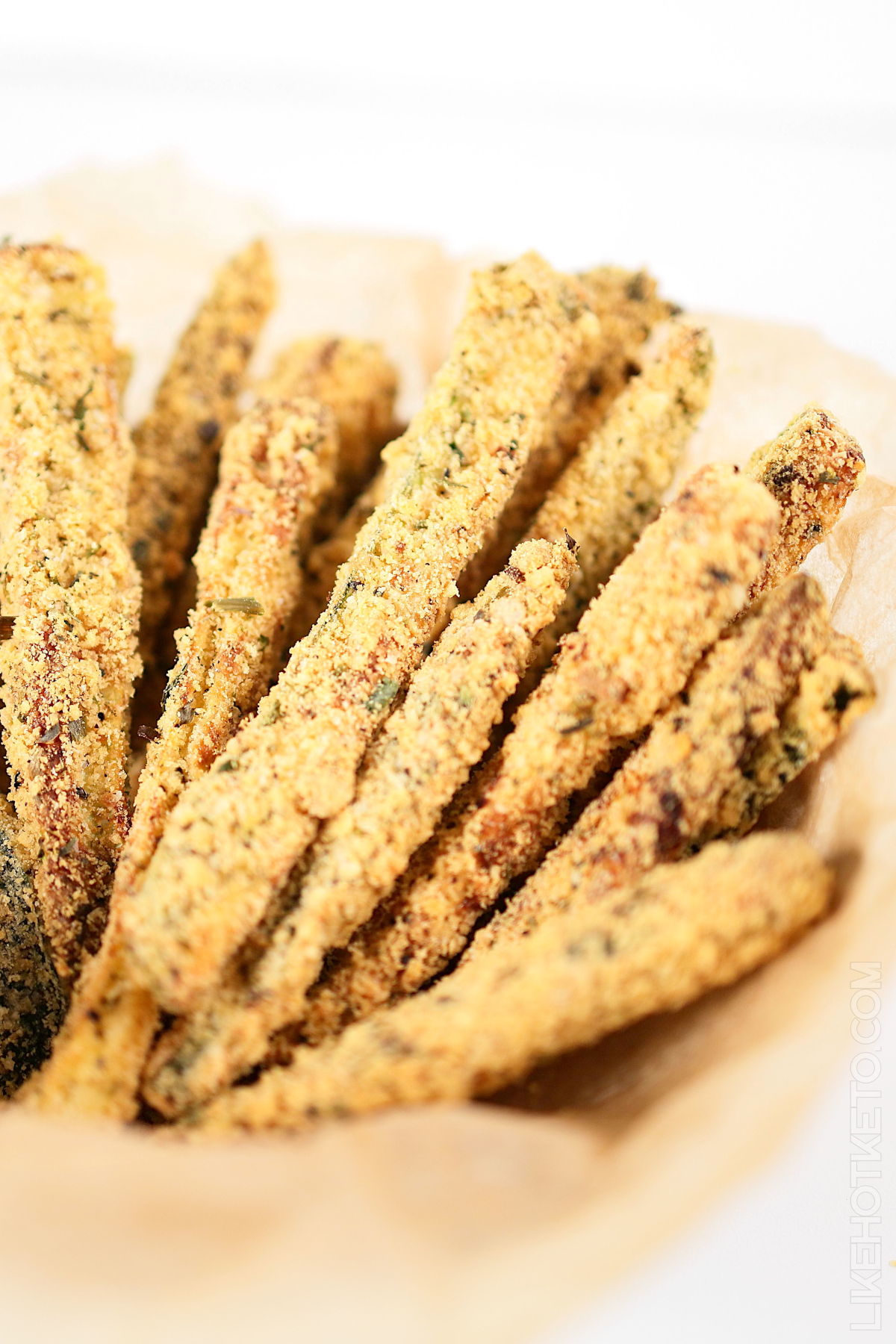 Baked zucchini fries served in a basket lined with parchment paper.