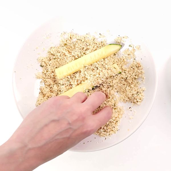 Zucchini slices in breading bowl.
