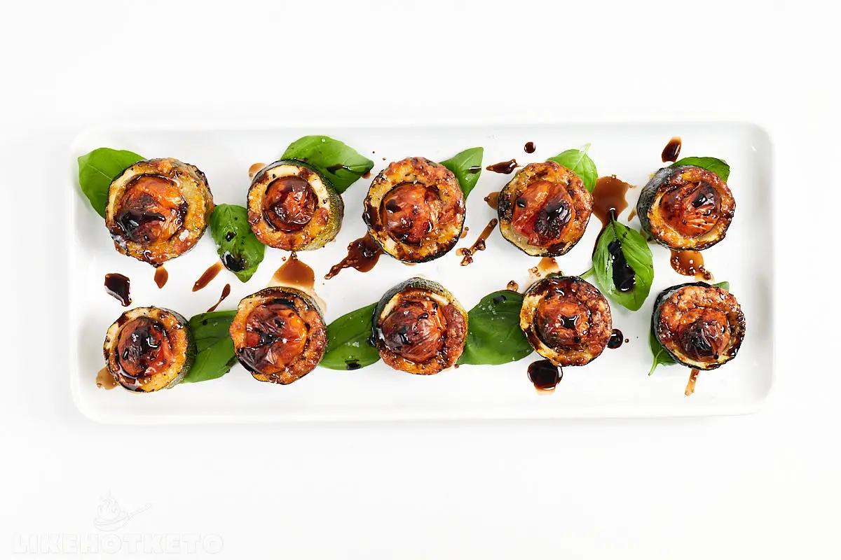 Zucchini caprese cups with balsamic on a long rectangular plate.