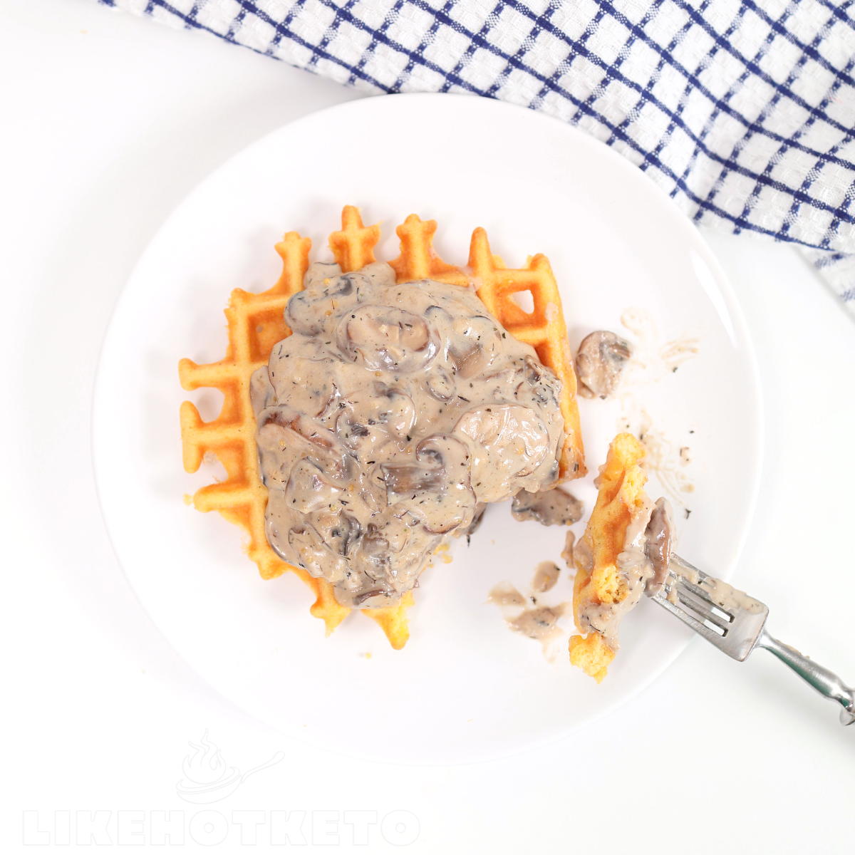 Chicken chaffle topped with mushroom sauce, bite taken with a fork.