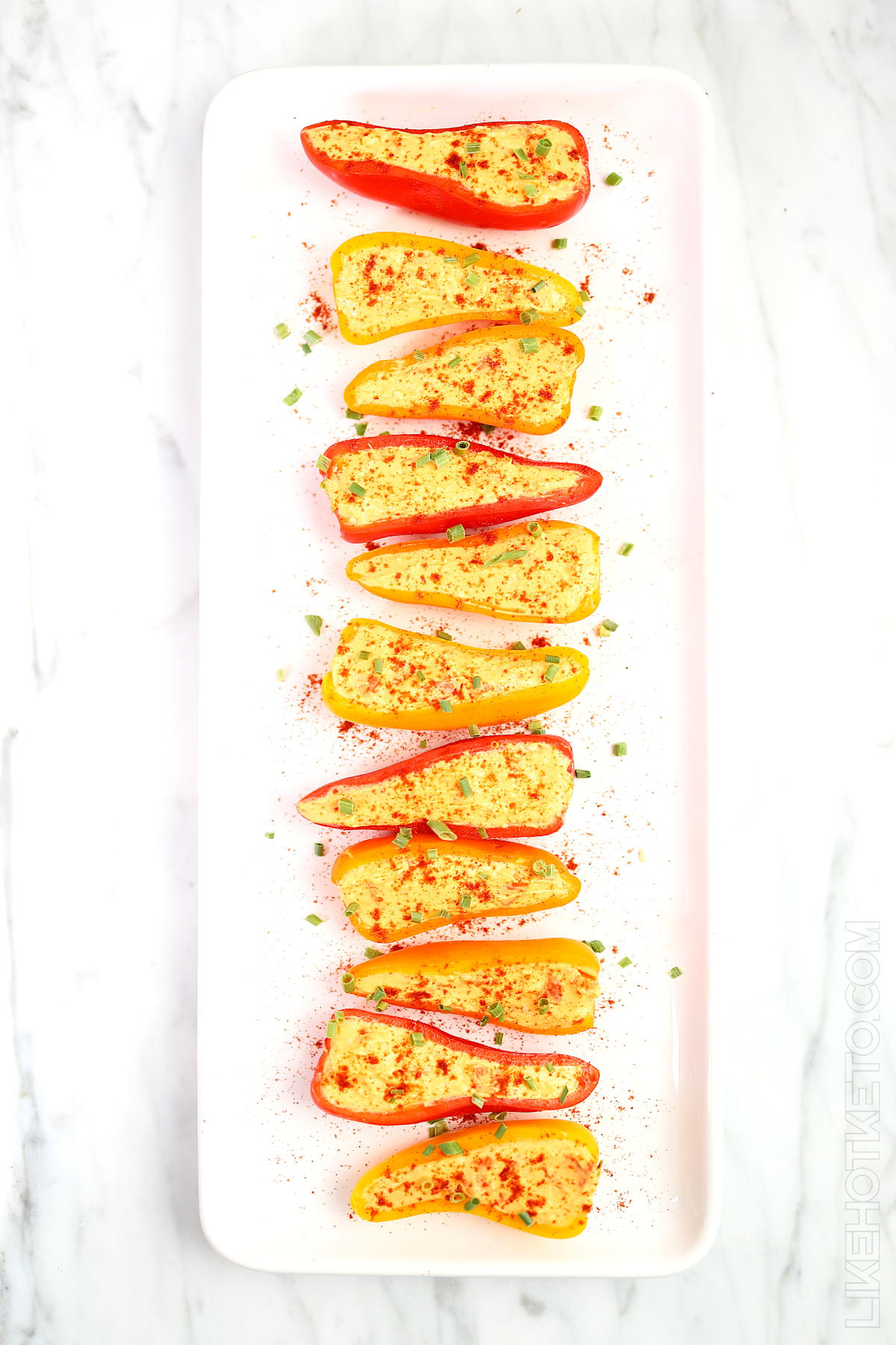 A long serving dish with colorful mini peppers stuffed with cheddar cream cheese and sriracha mix.