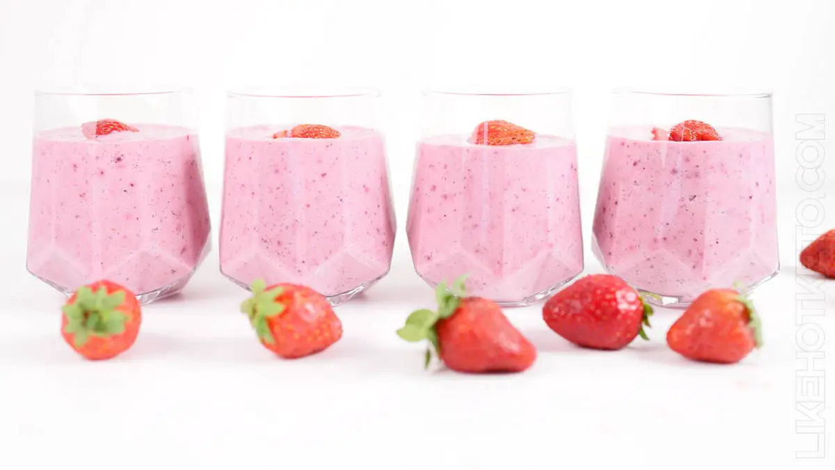 Dessert glasses with keto protein yogurt fluff lined up on a table with strawberries.