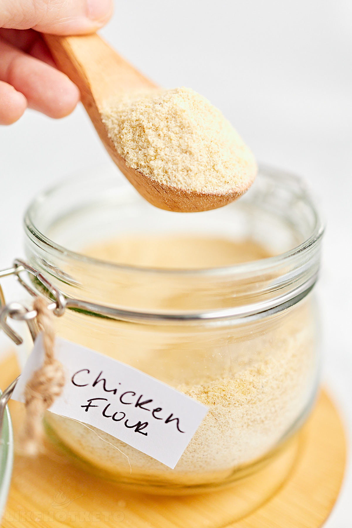 Wooden spoon with chicken powder over a labeled mason jar.