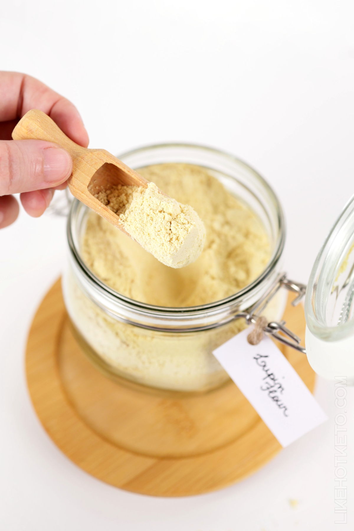 Taking lupin flour from a labeled jar with a wooden spoon.