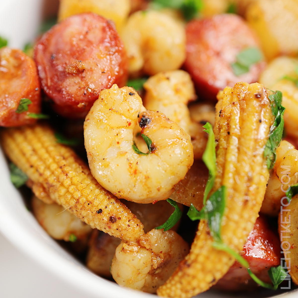 Shrimp boil with andouille sausages, turnips and baby corn garnished with chopped parsley.