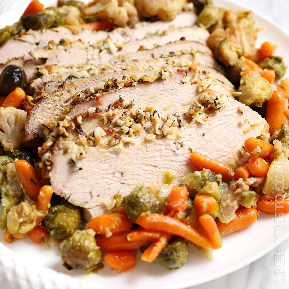 Sliced skinless turkey breast with garlic and herbs, in a bed of fall vegetables.