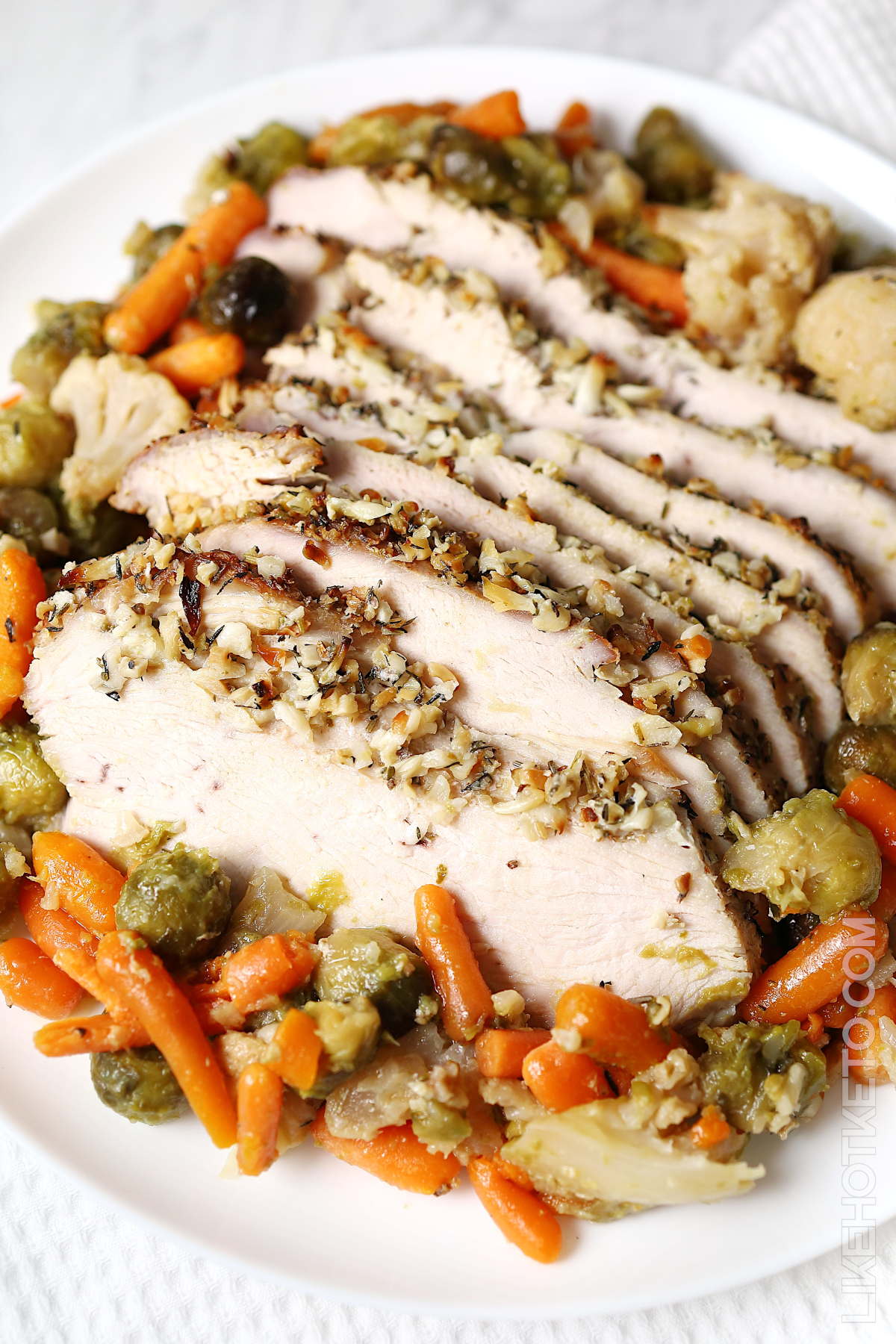 Roasted turkey breast, baby carrots, Brussel sprouts and cauliflower florets on a serving dish.