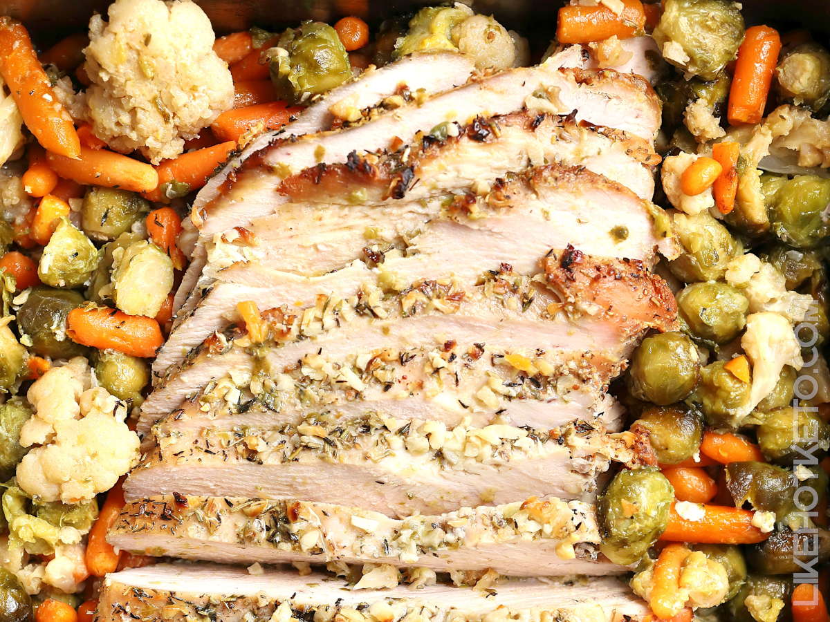 Turkey breast and fall vegetables roast in a baking pan.