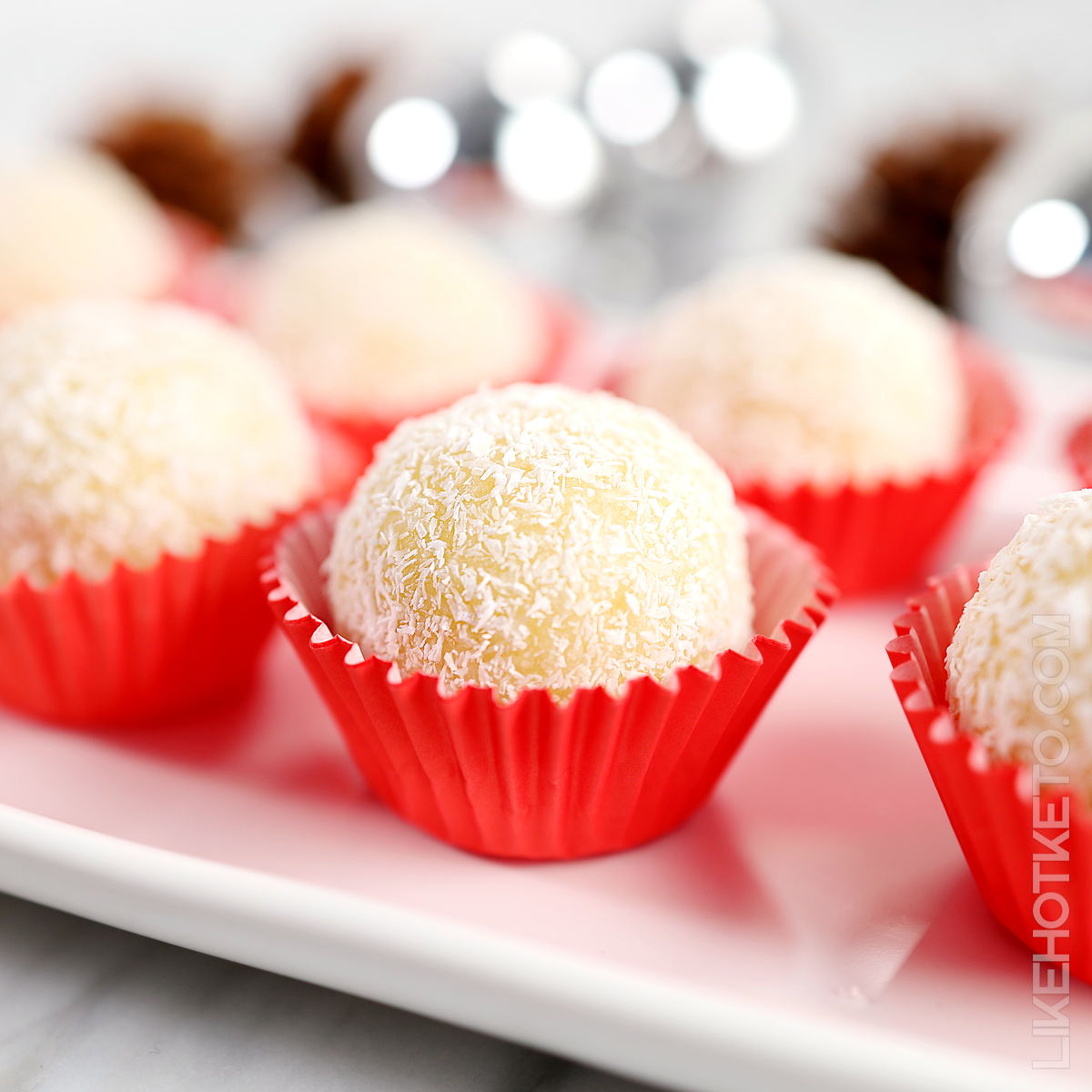 Keto snowballs white coconut truffles in red candy paper molds.