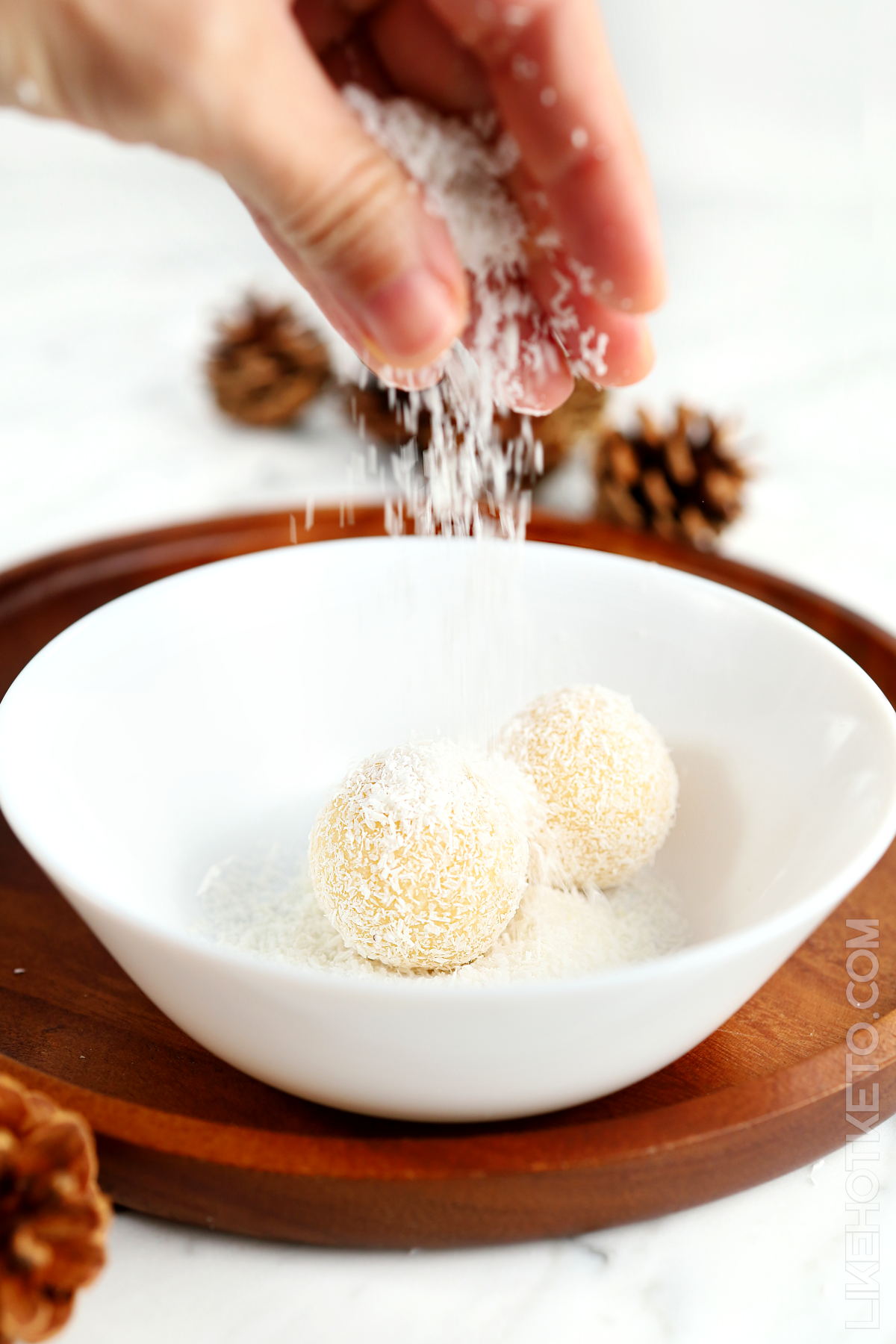 Dusting snowball truffles with shredded coconut.