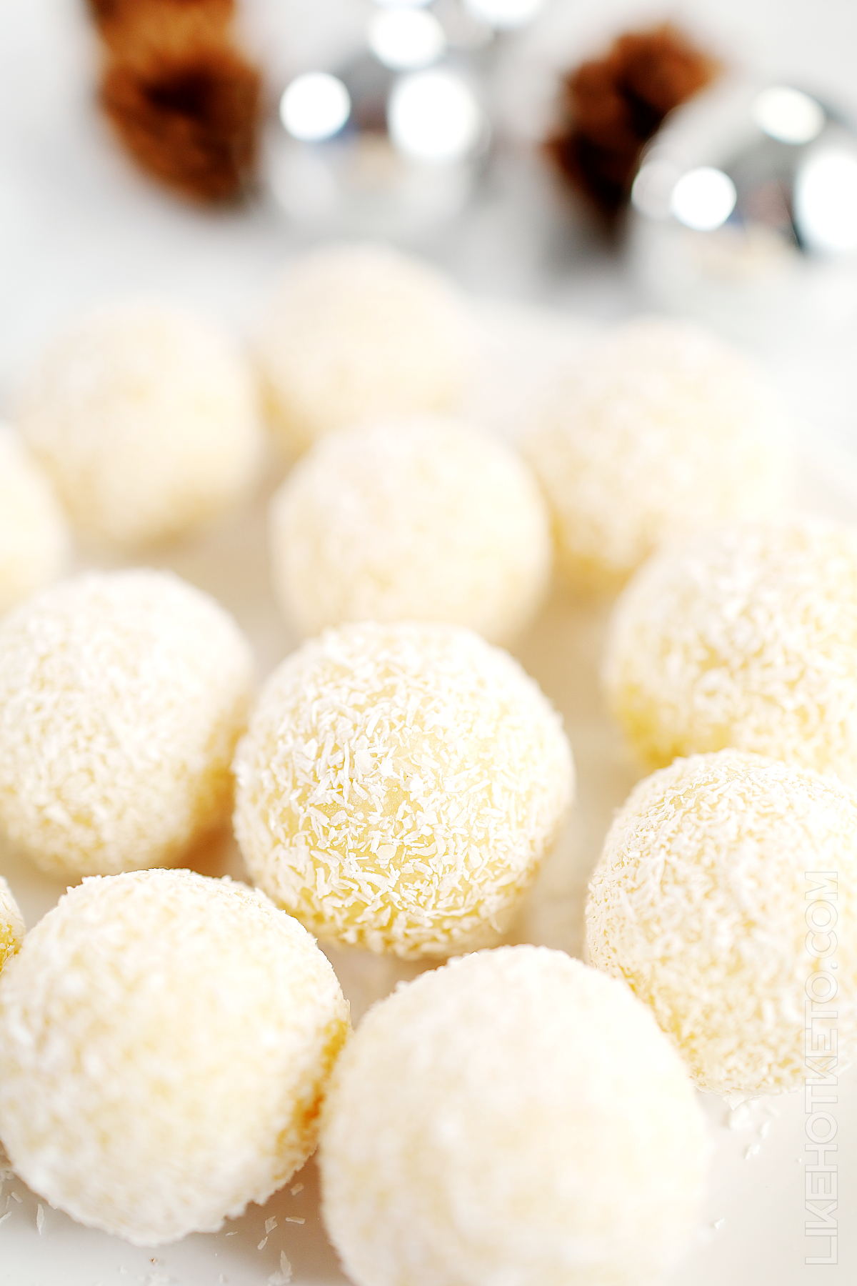 A plate full of no-bake snowball truffles with festive decoration in the background.