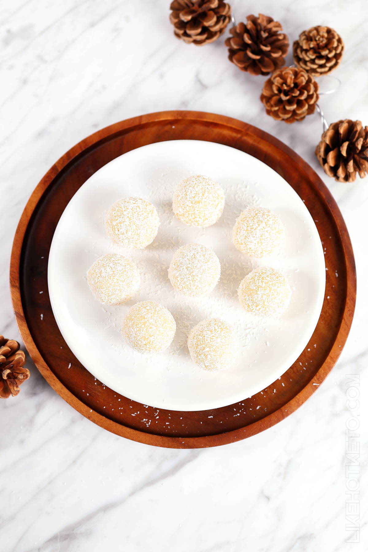 A plate full of no-bake snowball truffles with festive decoration in the background.