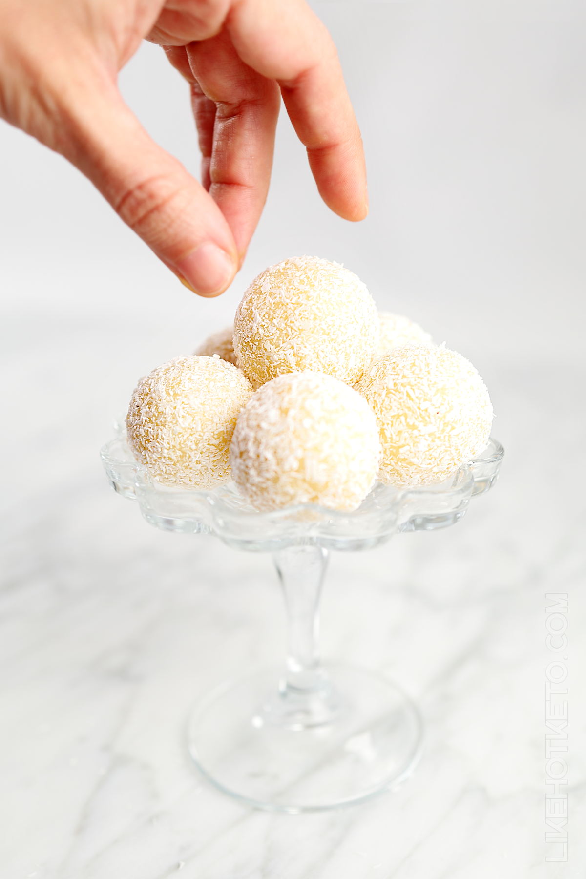 Keto coconut truffles arranged in a glass stand.