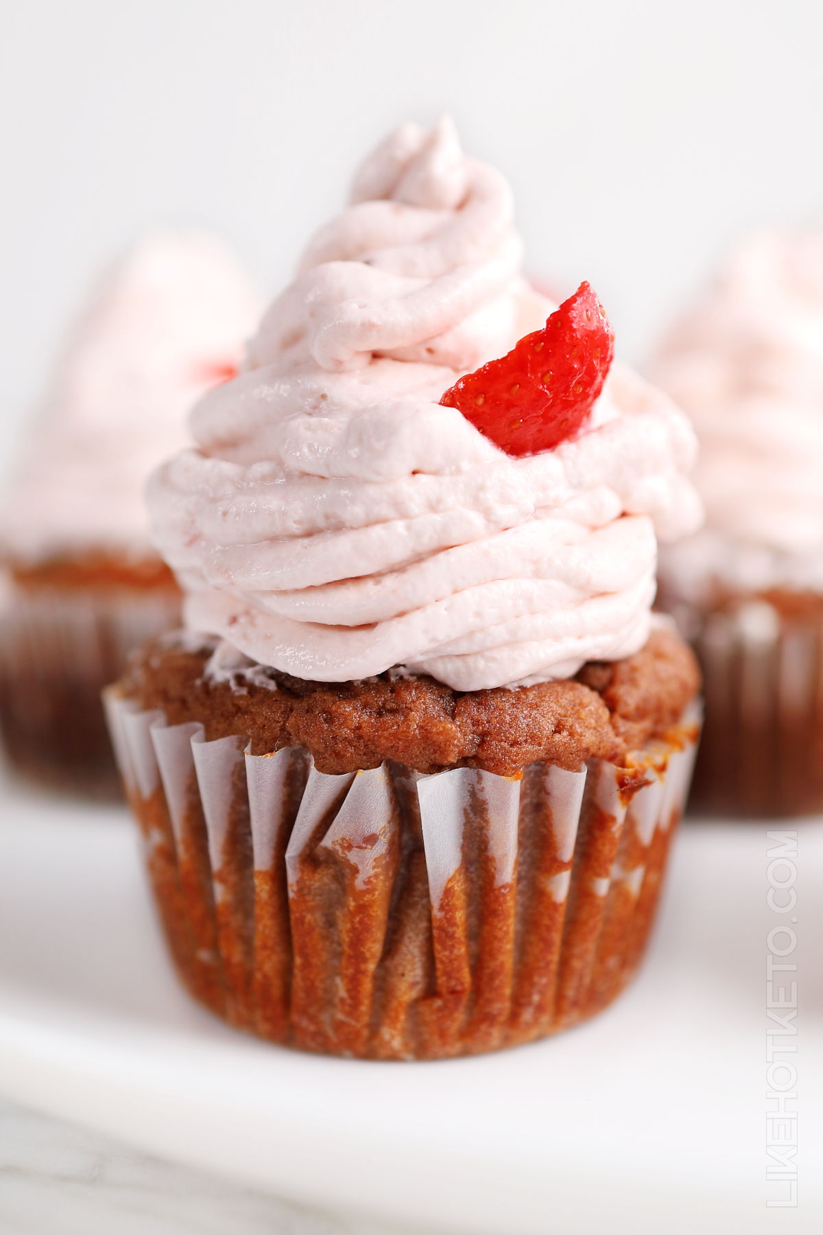 Keto strawberry cupcake with high pink strawberry frosting.