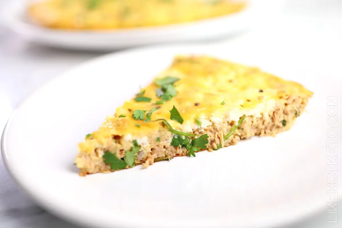 Slice of tuna frittata from theside, showing the tuna and creamy ricotta fillings.