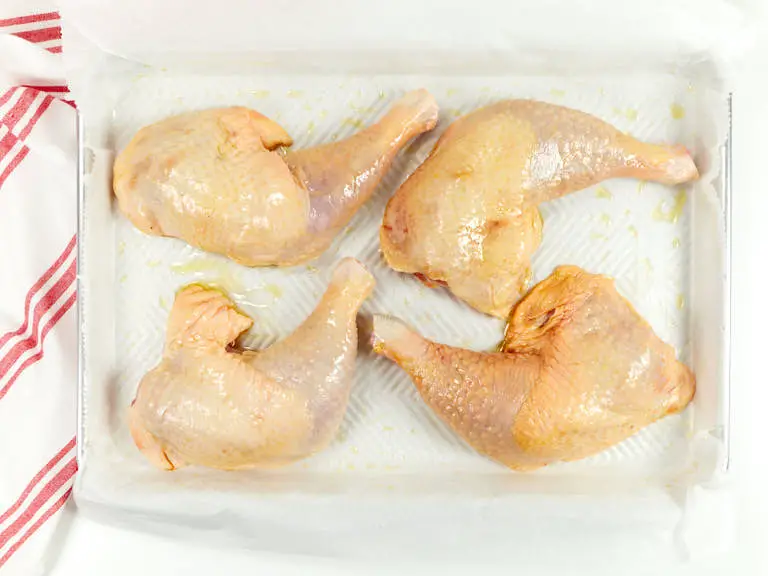 Chicken legs covered in olive oil.