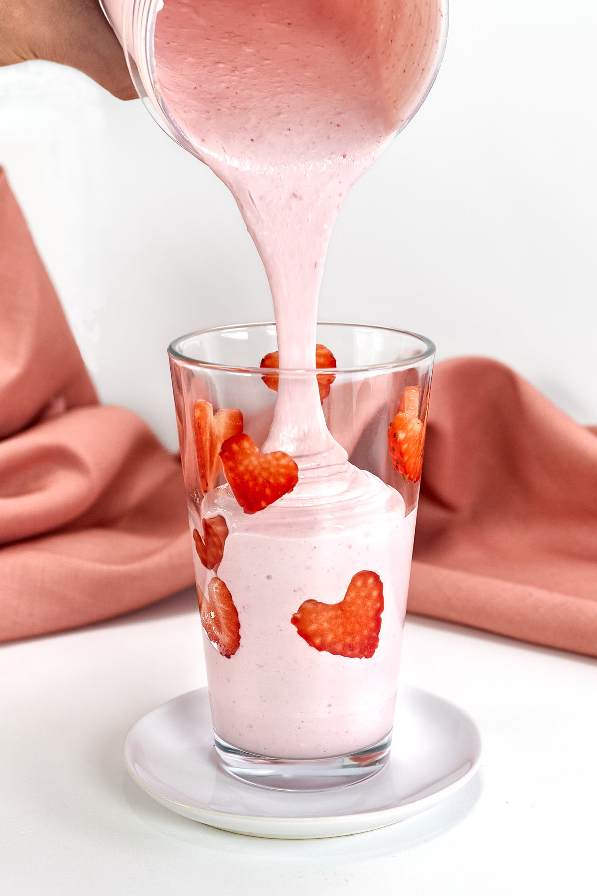 Pouring strawberry cottage cheese shake into glass.